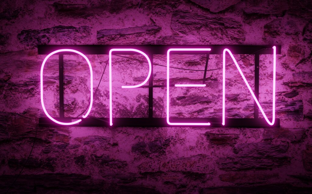 Render of a bright neon sign with an open purple caption indicating that the store, store, pub or restaurant is now open for business. Violet neon signage lights in 4k RGB.
